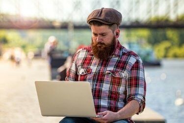 Madingas hipsteris jaunas vyras su nešiojamuoju kompiuteriu