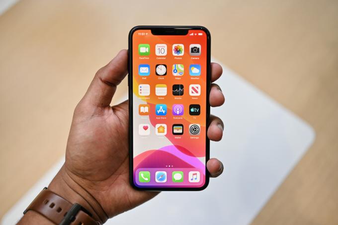 En hand håller en Apple iPhone 11 Pro Max som visar appar på skärmen.