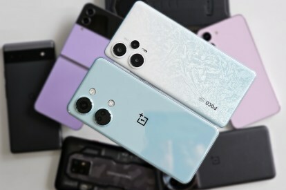 Xiaomi POCO F5 branco e OnePlus Nord 3 verde-azulado segurados em uma pilha de smartphones Android, incluindo OnePlus 11, Pixel 6a, Samsung Galaxy Z Flip 4, Galaxy S23.