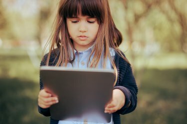 Маленькая девочка держит планшет для электронного обучения.