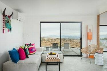 Ruang tamu minimalis yang terinspirasi dari gurun dengan sofa abu-abu muda dan bantal geometris neon