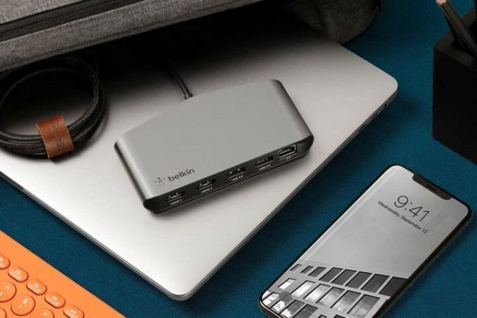 Belkin Thunderbolt 3 Dock Mini egy laptopon ülve egy utazótáska mellett.