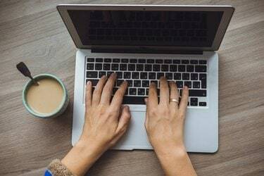 Laptop und Kaffeetasse in Mädchenhänden