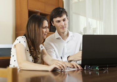 Pareja joven mirando documentos financieros en portátil