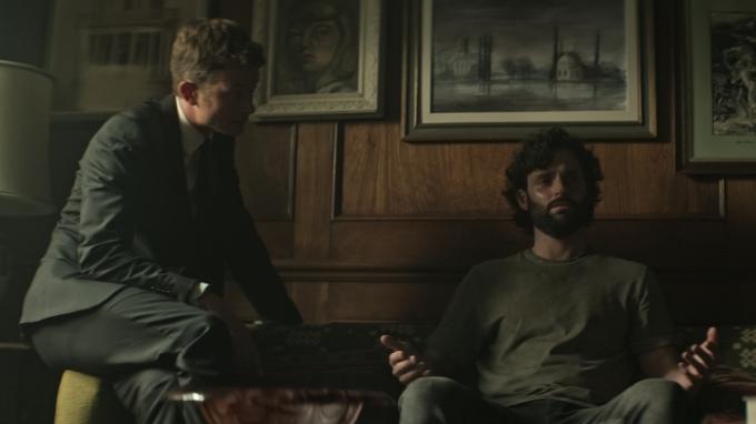 『You』シーズン4のワンシーンで、ソファで取り乱したジョーと、リースが彼の上にひざまずいている。