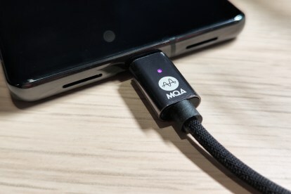 Een Zorloo Ztella MQA USB DAC aangesloten op een Google Pixel 7 Pro, met het MQA-logo en een magenta LED-lampje.