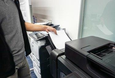 وضع رجل الأعمال الورقة الورقية في علبة الطابعة المكتبية لطباعة المستندات