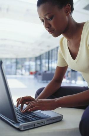 Sivuprofiili nuoresta naisesta, joka työskentelee kannettavalla tietokoneella