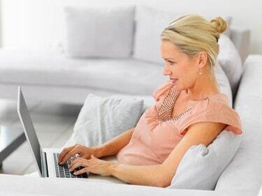 Aikuinen nainen käyttää kannettavaa tietokonetta Internetin selaamiseen
