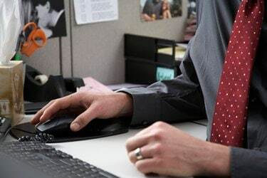 Pracownik biurowy korzystający z komputera przy biurku, w części środkowej, zbliżenie