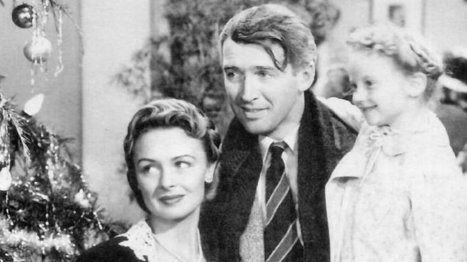 Jimmy Stewart dans le rôle de George Bailey tenant sa femme dans un bras et sa fille dans l'autre.