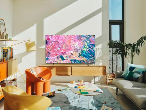 Televizorul inteligent Samsung Q60B QLED se află pe un dulap media dintr-o cameră de zi.