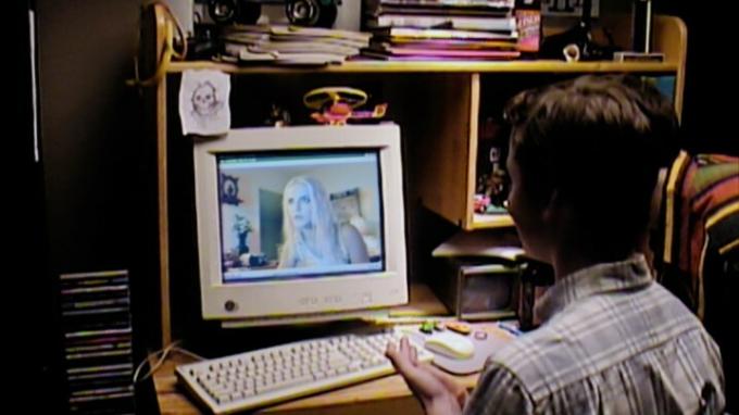En mandlig teenager sidder ved en computer i VHS99.