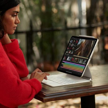 Een vrouw typt op een 11-inch Apple iPad Pro (2021) met toetsenbordbevestiging.