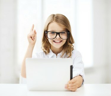 усмихнато момиче в очила с таблетен компютър в училище