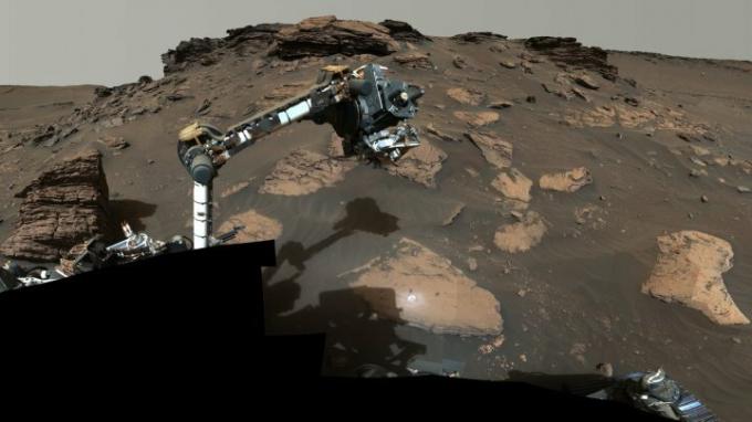 Rover Perseverance NASA používá svou robotickou ruku, aby objela skalnatý výběžek s názvem „Skinner Ridge“ v kráteru Jezero na Marsu. 