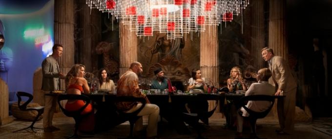 De cast van Glass Onion verzamelt zich rond een tafel in een scène uit de Netflix-film.