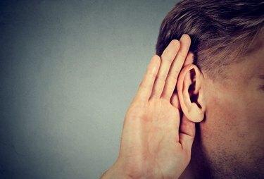 man houdt hand bij oor en luistert aandachtig