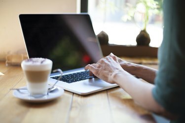 mulher de camisa verde digitando laptop com tela em branco