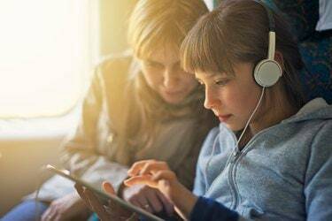Κορίτσι με τη μητέρα που ταξιδεύει στο τρένο και παίζει στο tablet