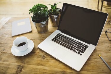 Laptop a šálek kávy na stole