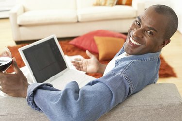 Homem maduro no sofá com laptop, sorrindo, retrato