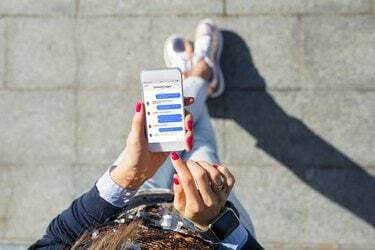 Жінка за допомогою програми обміну миттєвими повідомленнями на мобільному телефоні