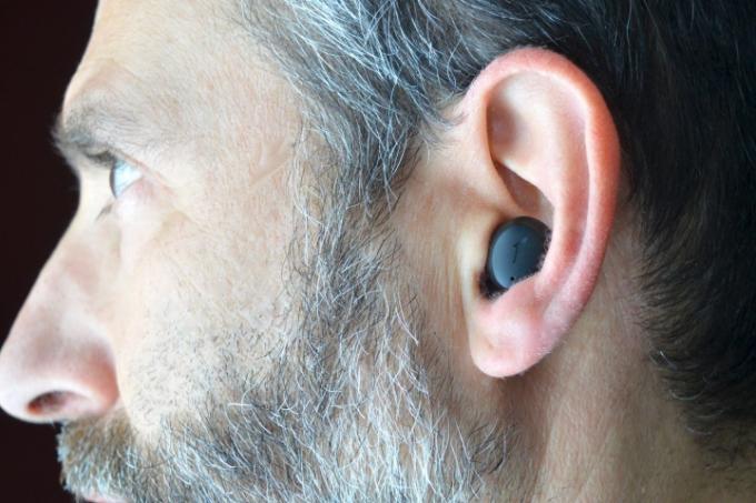Bir adam 1More ComfoBuds Mini kulaklık takıyor.