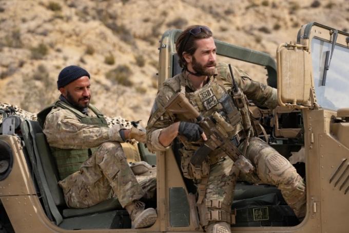 Jake Gyllenhaal siede sul lato di una jeep in una scena di The Covenant.