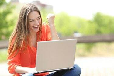 Femeie euforică în căutarea unui loc de muncă cu un laptop într-un parc