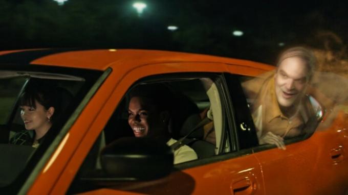 Průhledný duch v podání Davida Harboura vystrčí hlavu z okna auta ve scéně z We Have A Ghost.