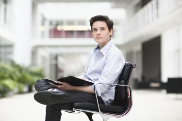 Nastoletni chłopiec siedzi na krześle biurowym, odwracając wzrok