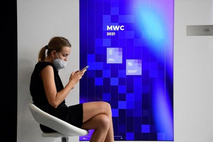 Une femme portant un masque utilise son téléphone au salon Mobile World Congress (MWC) à Barcelone le 1er juillet 2021.