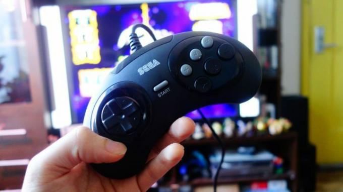 Pengontrol Sega Genesis Mini diangkat di depan TV.