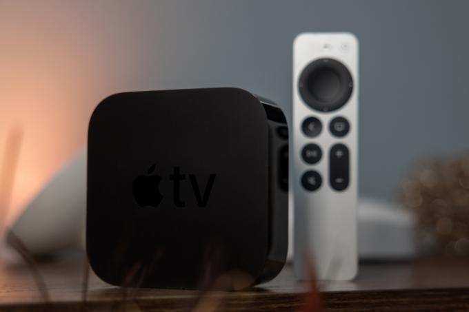 Bir Apple TV 4K, masadaki uzaktan kumandanın yanında dik duruyor.