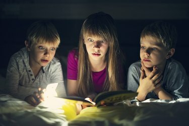 Barn som läser en bok med läskiga historier på natten