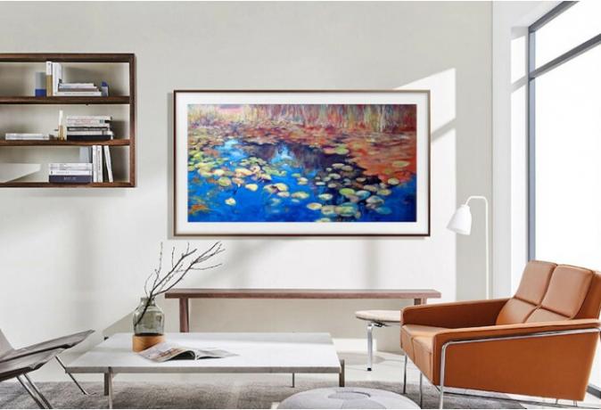 50 collu Samsung Frame televizors karājas pie viesistabas sienas, kurā redzama māksla.