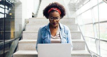 ノートパソコンを使用して階段に座っている焦点を当てた若いアフリカの学生