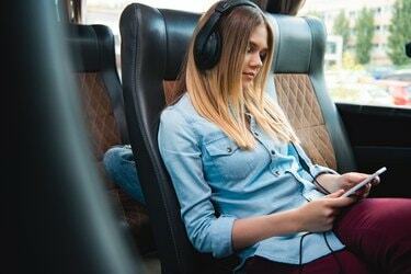 Mujer en auriculares para dormir y escuchar música con el teléfono inteligente durante el viaje en autobús de viaje