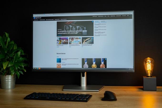 Dell 32 4K USB-C Hub-bildskärm som sitter på skrivbordet bredvid växt och ljus.