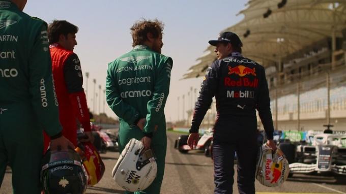 F1: Drive to Survive のシーズン 5 のシーンで、レッドブル チームのマックス フェルスタッペンを含む数人のドライバーがヘルメットを手にトラックに沿って歩いています。