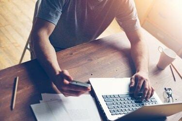 Homem com celular e laptop em loft moderno