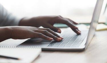 Zwarte vrouw typt op het toetsenbord van de laptop terwijl ze op kantoor werkt
