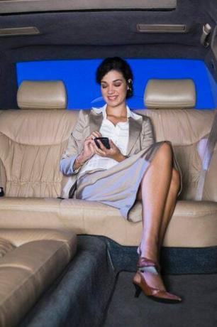 Femeie de afaceri cu telefonul mobil în limuzină