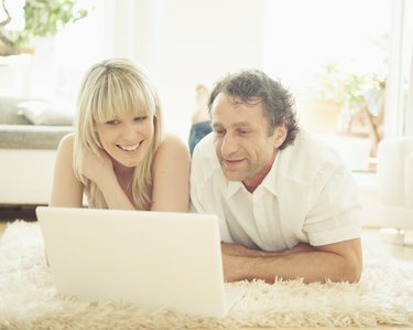 Uomo e donna che usano il laptop sul tappeto