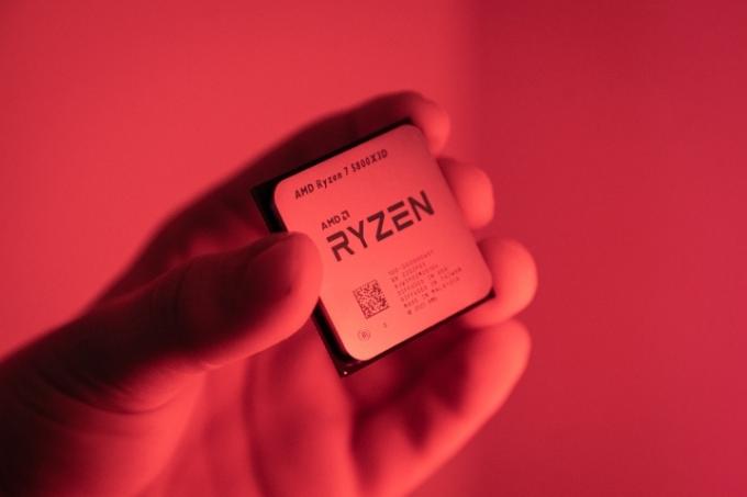 赤いライトの中で Ryzen 7 5800X3D を持っている人。
