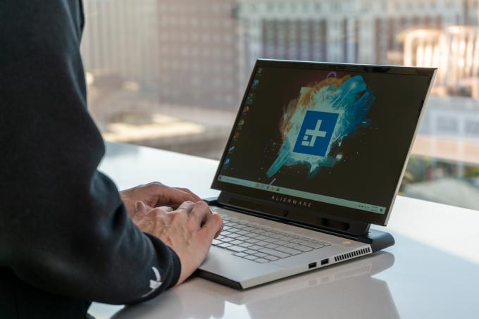 En person skriver på en Alienware M15 vid ett skrivbord.