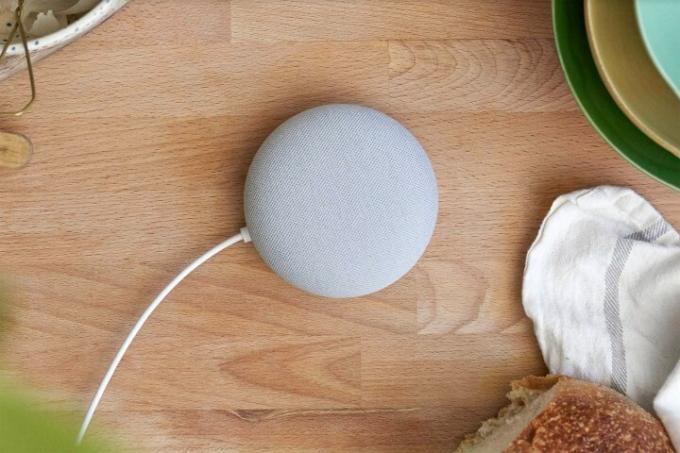 En grå Google Nest Mini som sitter på en köksbänk.
