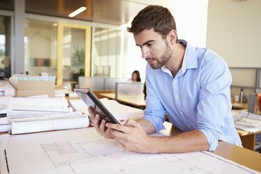 Bărbat arhitect cu tabletă digitală care studiază în birou