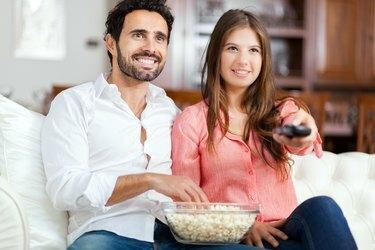 Mladý pár sleduje televíziu a jedáva popcorn